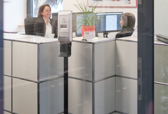 Blick durch eine Glasscheibe ins Büro von ewes & partner, in dem zwei Mitarbeiterinnen sitzen