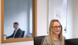 Blick auf eine Mitarbeiterin von ewes & partner bei der Arbeit, im Hintergrund sitzt ein Kollege